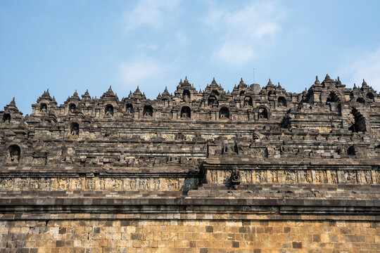 Borobudur temple stone carvings and stupas against blue sky