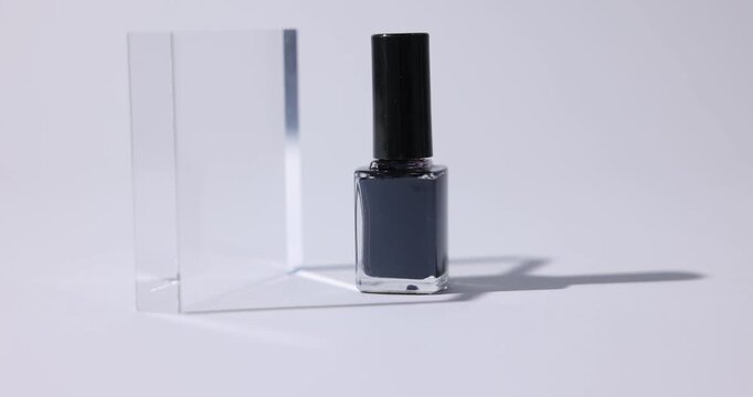 Stylish presentation of nail polish in bottle on white background, closeup. Camera moving right