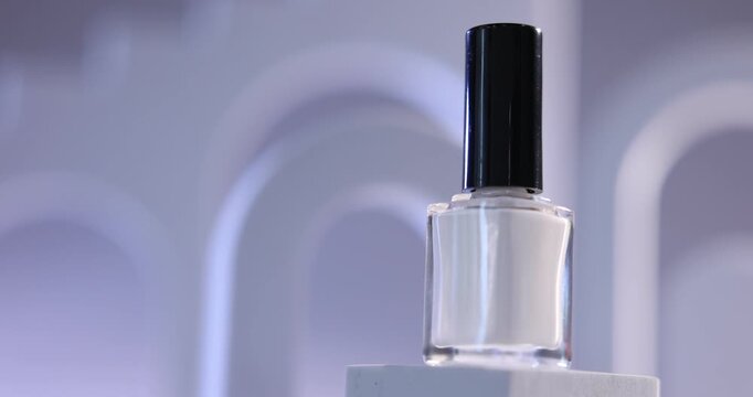 Stylish presentation of nail polish in bottle on podium against color background, closeup. Space for text
