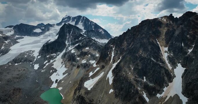 Aerial drone footage of Wedgemount Lake in British Columbia, Canada, showcasing the turquoise alpine lake surrounded by rugged mountains, rocky terrain, and pristine wilderness. Cinematic scenic lands