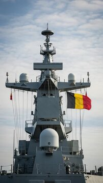 Modern Belgian navy warship superstructure and radar mast with flying national flag representing defense technology