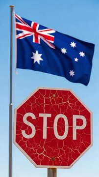 Weathered red stop sign and Australian flag fluttering against a clear blue sky, symbolizing national rules, traffic safety, and regulations