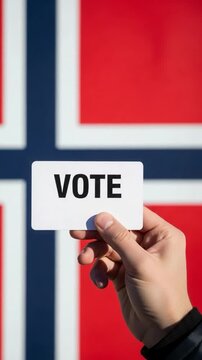 Norwegian citizen holding a card with the word vote in front of the national flag representing democratic elections in Norway