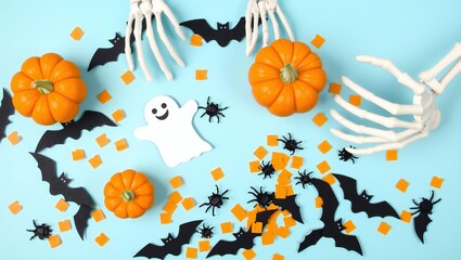 Fototapeta premium Halloween party decorations with pumpkins ghost bats and skeleton hands on a light green background