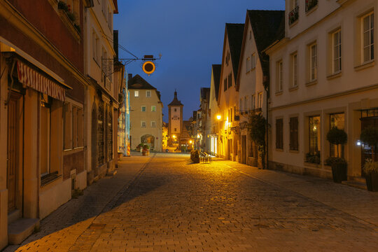 Half-timbered houses and cobblestone streets illuminated by warm streetlights during blue hour in Rothenburg ob der Tauber, Germany.