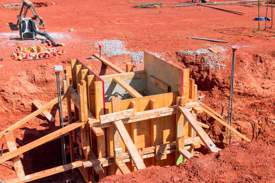 Workers are preparing for concrete pouring at construction site on red soil heavy machinery is nearby.