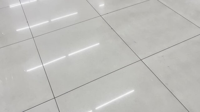 Glossy marble tile floor with bright ceiling light reflection