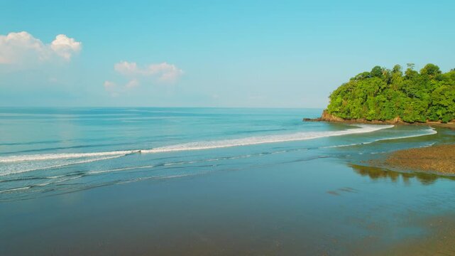 Aerial view of calm ocean waves rolling onto sandy shore Hermosa Beach in Costa Rica