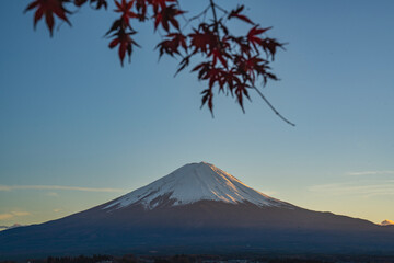Fototapeta premium Majestic Mount Fuji rises above the tranquil lake at golden hour, creating a breathtaking Japanese landscape of mountains, water, and soft evening light. 