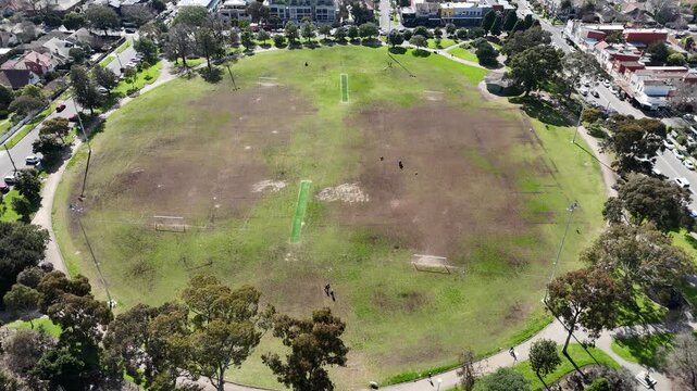 Aerial view looking down at the large oval reserve, sports pitch, people relaxing with pets in an off-leash dog area surrounded by walking paths&nbsp;at Central Park in Malvern East, Melbourne, Australia