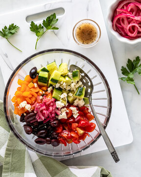 Fresh ingredients in a glass bowl ready for mixing a mediterranean salad