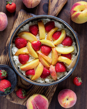 Top down view of a prepared homemade strawberry peach cake ready for baking.