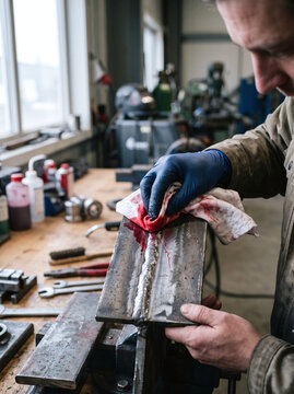 Inspector performing dye penetrant testing on welded steel in a workshop