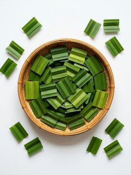 Chopped fresh pandanus leaves in a round rattan tray isolated on white background flat lay