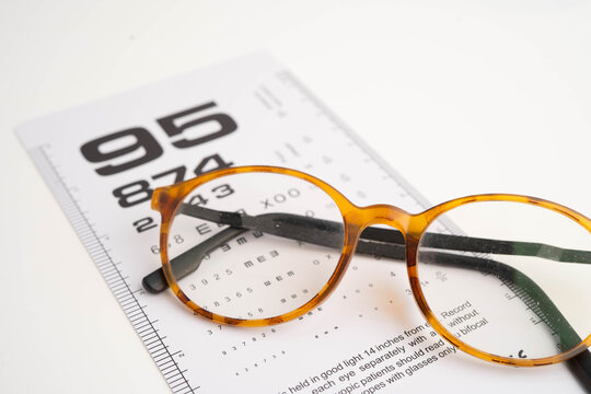 Glasses on eye testing exam chart to check eyesight accuracy of reading.