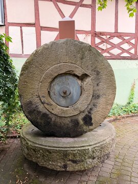 Alter M&uuml;hlstein an einem Fachwerkhaus.