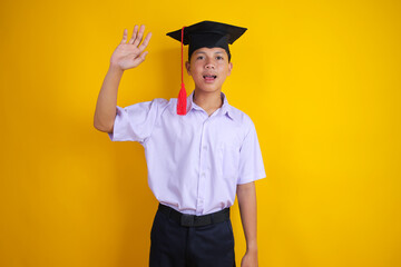 Indonesian Student in School Uniform and Mortarboard Waving hand in Greeting Gesture © Gatot