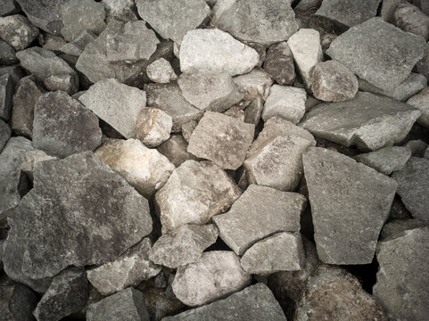 Close-up, top-down view of a pile of raw, grey riprap stones and jagged broken rocks, showcasing rugged textures and natural shapes suitable for construction or background.
