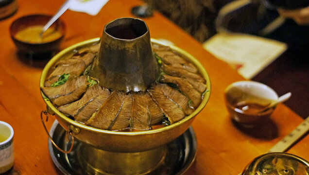 Shangri-La,China - February 18, 2012: A traditional Tibetan style copper hotpot loaded with sliced yak meat and greens.