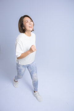[水色背景]笑顔でランニングやウォーキングを楽しむ女性、健康維持のために運動するアクティブな40代