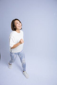 [水色背景]笑顔でランニングやウォーキングを楽しむ女性、健康維持のために運動するアクティブな40代
