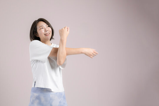  [ピンク背景]更年期も健康のために笑顔でストレッチする40代女性、運動前に体をほぐすのフィットネス