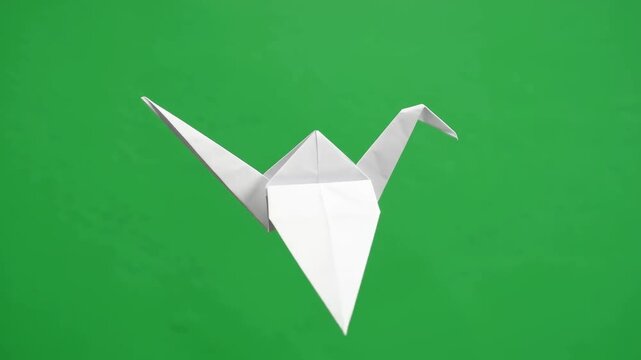 A handcrafted paper bird resting peacefully upon a vibrant green surface highlighting traditional folding techniques and artistic expression through folded paper formations in a natural setting