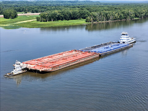 Set of liquid cargo barges being guided by a small service tug