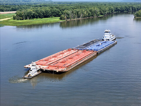 Set of liquid cargo barges being guided by a small service tug