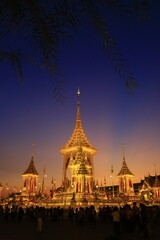 Fototapeta premium Phra Merumat at twilight with visitors and tree branches framing the golden structure