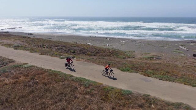 A mature man and woman enjoy biking on the Coastal Trail in Fort Bragg California with beautiful views of the Pacific Ocean.