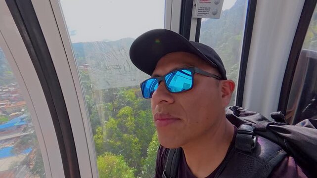 Male tourist enjoying the view from metrocable gondola in medellin