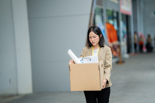 A businessman who has lost his job walks out of the office carrying a box of his belongings, feeling sad and frustrated. He faces a career crisis, stress, uncertainty, and financial difficulties.