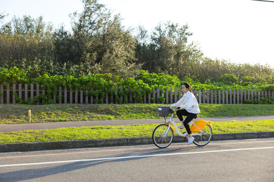 Woman riding a rental bicycle along a scenic park path outdoors in Taiwan