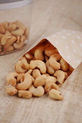 Fototapeta premium Cashews spilling from a bag on a wooden table