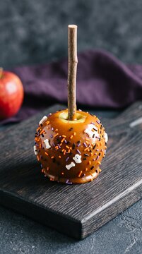 Caramel apple decorated with colorful sprinkles and halloween themed toppings