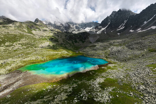 Turquoise alpine lake surrounded by rocky mountains and cloudy sky