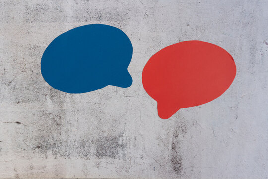 Blue and red speech bubbles painted on gritty concrete surface