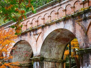 Naklejka premium Red Brick Aqueduct Arches at Nanzenji Suirokaku with Autumn Foliage, Kyoto
