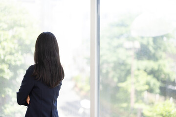 Fototapeta premium Young Japanese businesswoman standing with her arms crossed by a bright window