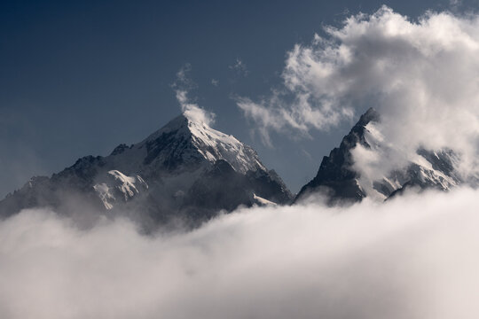 Snow Covered Mountain Peaks Rising Above Thick White Clouds