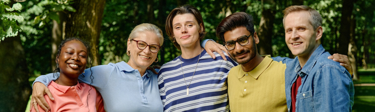Portrait of diverse multiethnic group smiling during outdoor psychotherapy session in park, representing mental wellbeing and community support, ideal for healthcare marketing, header