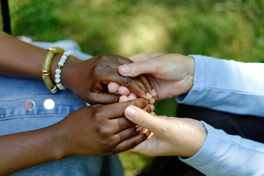 Caucasian therapist holding hands of Black female patient during outdoor psychotherapy session in park, representing mental health support and diverse counseling services, close up shot