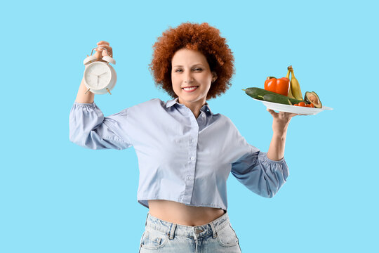 Healthy eating and intermittent fasting, woman holding alarm clock and plate of fresh vegetables and fruits for weight loss and nutrition management