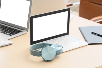 Fototapeta premium Remote work and digital learning, laptop with blank screen and headphones on office desk for online communication and virtual meeting preparation