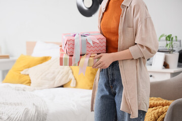 Naklejka premium Gift giving and celebration, person holding wrapped presents for birthday or holiday surprise in a cozy home bedroom setting