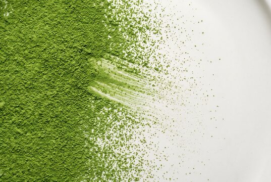 Abstract overhead texture of vivid jade matcha powder swept smoothly across a bone-white surface, transitioning from a dense saturated green field on the left to a fine dusting.