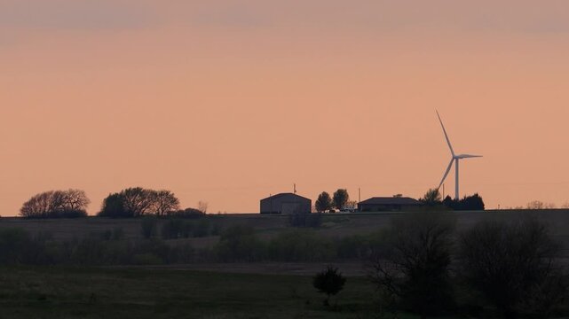 Wind Turbine Turns Beside Rural Kansas Farm at Dusk