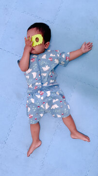 Vertical portrait of a baby resting on a blue playmat