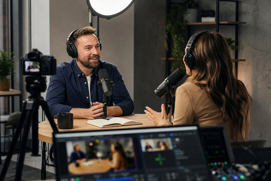 Podcast Hosts Recording a Professional Live Streaming Interview in a Modern Studio with Headphones, Broadcast Microphones, Camera, Ring Light and Video Mixing Console